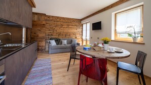 A compact living space with a kitchen, dining area, and a cozy seating area. - CHALET INES - Appartamento 4 (Vodo Cadore)