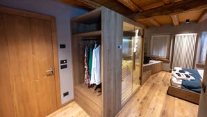 A bedroom with a wooden wardrobe, a bed, and a built-in bench. - TEVERONE SUITES & WELLNESS - Camera Gallo Forcello (Lamosano)