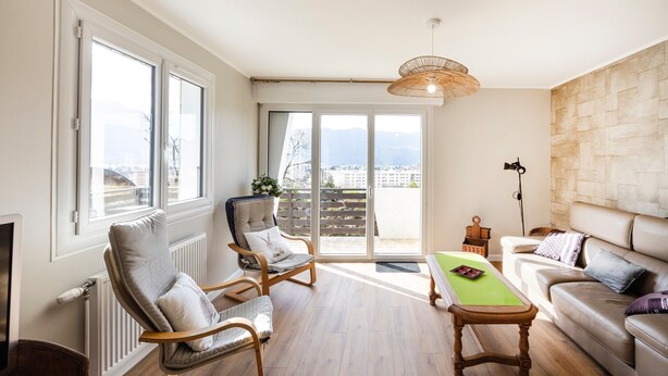 Un salón espacioso con vistas, una chimenea, un sofá, un sillón y una mesa.