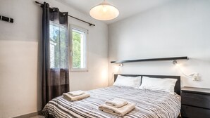A bedroom with a bed, a window with curtains, a bedside table, and a wall-mounted light fixture. - Apartment "Green Park B18" with Private Terraces, Shared Pool and Wi-Fi (Son Parc)