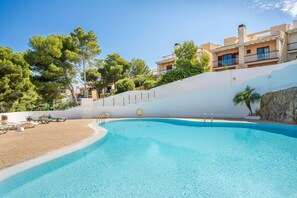 A swimming pool with lounge chairs and a lifebuoy, surrounded by buildings and trees.