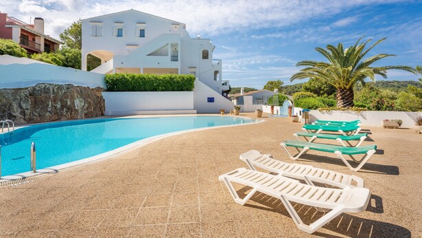 A swimming pool with lounge chairs, a modern building, and a palm tree. - Apartment "Green Park B18" with Private Terraces, Shared Pool and Wi-Fi (Son Parc)