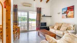 A living room with a sofa, a wooden coffee table, a TV, and a painting on the wall. - Apartment "Green Park B18" with Private Terraces, Shared Pool and Wi-Fi (Son Parc)