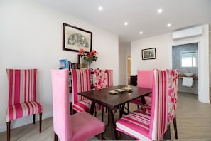 A dining area with a wooden table and striped chairs, a vase with flowers, and a framed picture on the wall.