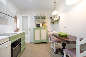 A compact kitchen with a microwave, a green cabinet, and a dining area with a table and chairs.