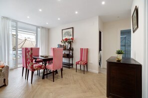 A dining area with a table, chairs, and a bookshelf. - Accessible Holiday Apartment 'Ancha 9' with Private Terrace & A/C (Sanlúcar de Barrameda)