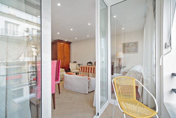 A room with a bed, a chair, a table, and a window.