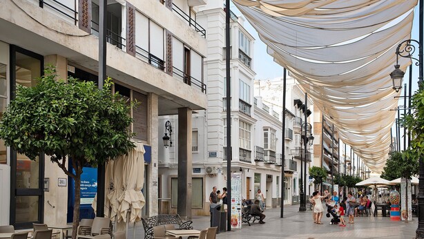 A street with outdoor seating, buildings, and a canopy.