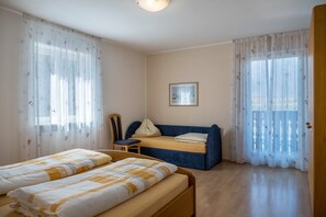 Una habitación con dos camas, un sofá, una silla y un cuadro en la pared.