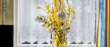 A vase with flowers on a windowsill.