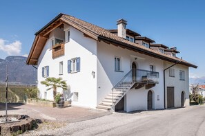 Una casa de dos pisos con un balcón, una escalera y vistas a las montañas.