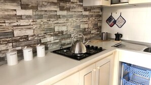 A kitchen with a gas stove, kettle, and white storage containers. - Holiday Apartment 'Beba' with Private Garden and Wi-Fi (Lido di Jesolo)