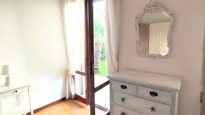 A room with a white dresser, a mirror, and a door leading to an outdoor area. - Holiday Apartment 'Beba' with Private Garden and Wi-Fi (Lido di Jesolo)