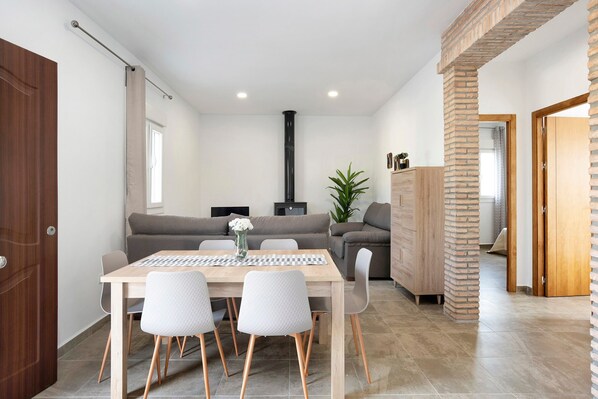 A modern living space with a dining area, sofa, and a fireplace.