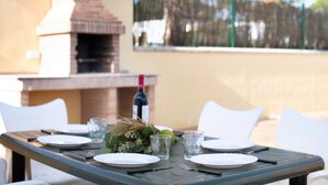 A dining table set outdoors with plates, glasses, and a bottle, surrounded by white chairs. - Holiday Home "Villa Montenmedio - Paula" with Mountain View & Pool (El Soto)