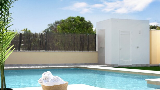 A swimming pool with a white utility box and a basket of towels.