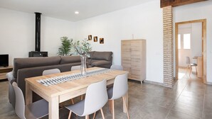 A modern living room with a sofa, dining table, chairs, a TV, and a fireplace.