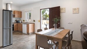 A modern kitchen with wooden cabinets, a dishwasher, and a dining area with a table and chairs.
