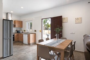 Una cocina moderna con armarios de madera, lavavajillas y una zona de comedor con mesa y sillas.