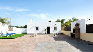 A courtyard with a white building, outdoor seating, and a brick oven. - Pet-Friendly Holiday Home "Villa Montenmedio - Carmelo" with Mountain View & Pool (El Soto)