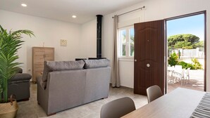 A living area with a sofa, a dining table, a wooden cabinet, and a large window. - Holiday Home "Villa Montemedio - Paco" with Private Pool and Mountain View (El Soto)