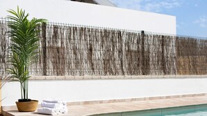 A pool area with a white wall, a woven fence, a potted plant, and rolled towels. - Holiday Home "Villa Montemedio - Paco" with Private Pool and Mountain View (El Soto)