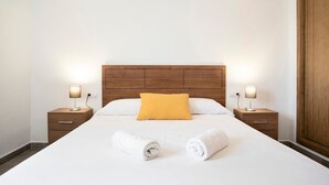A neatly made bed with white linens, a wooden headboard, and two bedside lamps. - Holiday Home "Villa Montemedio - Paco" with Private Pool and Mountain View (El Soto)
