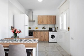 Une cuisine compacte équipée d’un four à micro-ondes, d’un lave-linge, de meubles en bois et d’un coin repas avec un jeu d’échecs.