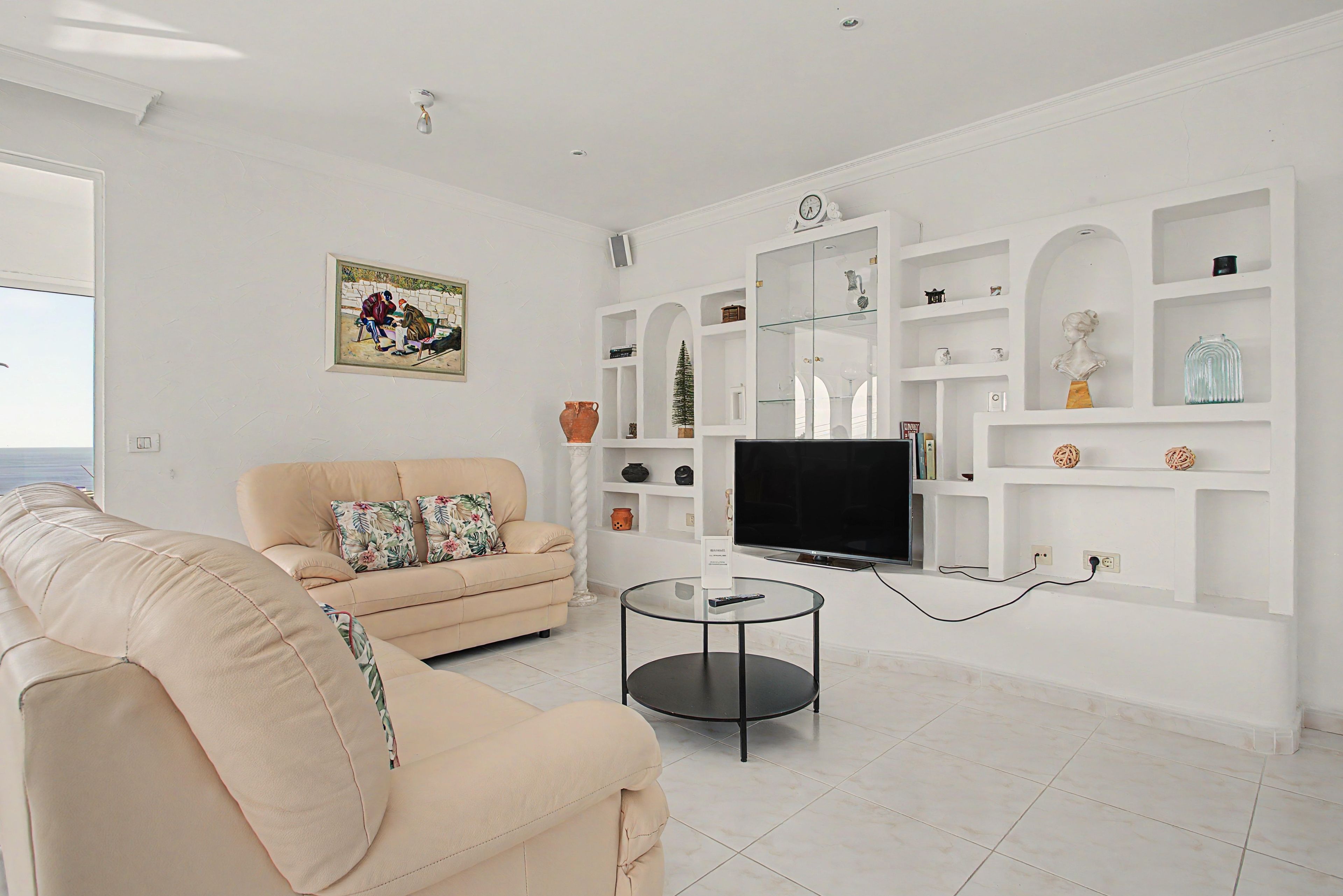 A living room with a sofa, a television, and a glass coffee table.