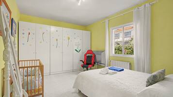 A bedroom with a bed, a desk, a chair, a wardrobe, and a window with curtains.