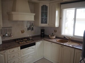 A kitchen with white cabinets, a gas stove, a coffee maker, and a window with a view. - Vacation Home "Hibiscus" with Sea View, Pool & Wi-Fi (santa ursula)