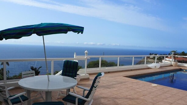 A terrace with a pool, a table, and chairs, overlooking a body of water. - Vacation Home "Hibiscus" with Sea View, Pool & Wi-Fi (santa ursula)