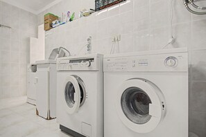 A laundry room with two front-loading washing machines and a dryer.