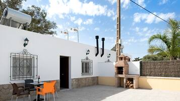 Un patio con posti a sedere all'aperto, un forno a mattoni e un muro in pietra.