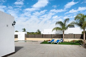 A pool area with two blue lounge chairs, a small pool, and a white building with a black fence. - Pet-Friendly Holiday Home "Villa Montenmedio 2" with Mountain View & Pool (El Soto)