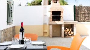 Une table à manger dressée avec des assiettes, des verres et des couverts, une bouteille de vin et une chaise orange.