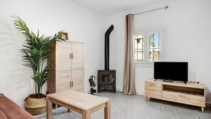 Un salon avec un téléviseur, des meubles en bois, une plante, une cheminée et une fenêtre.