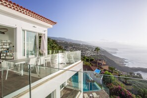 Un edificio moderno con balcón de cristal que ofrece vistas al paisaje costero.
