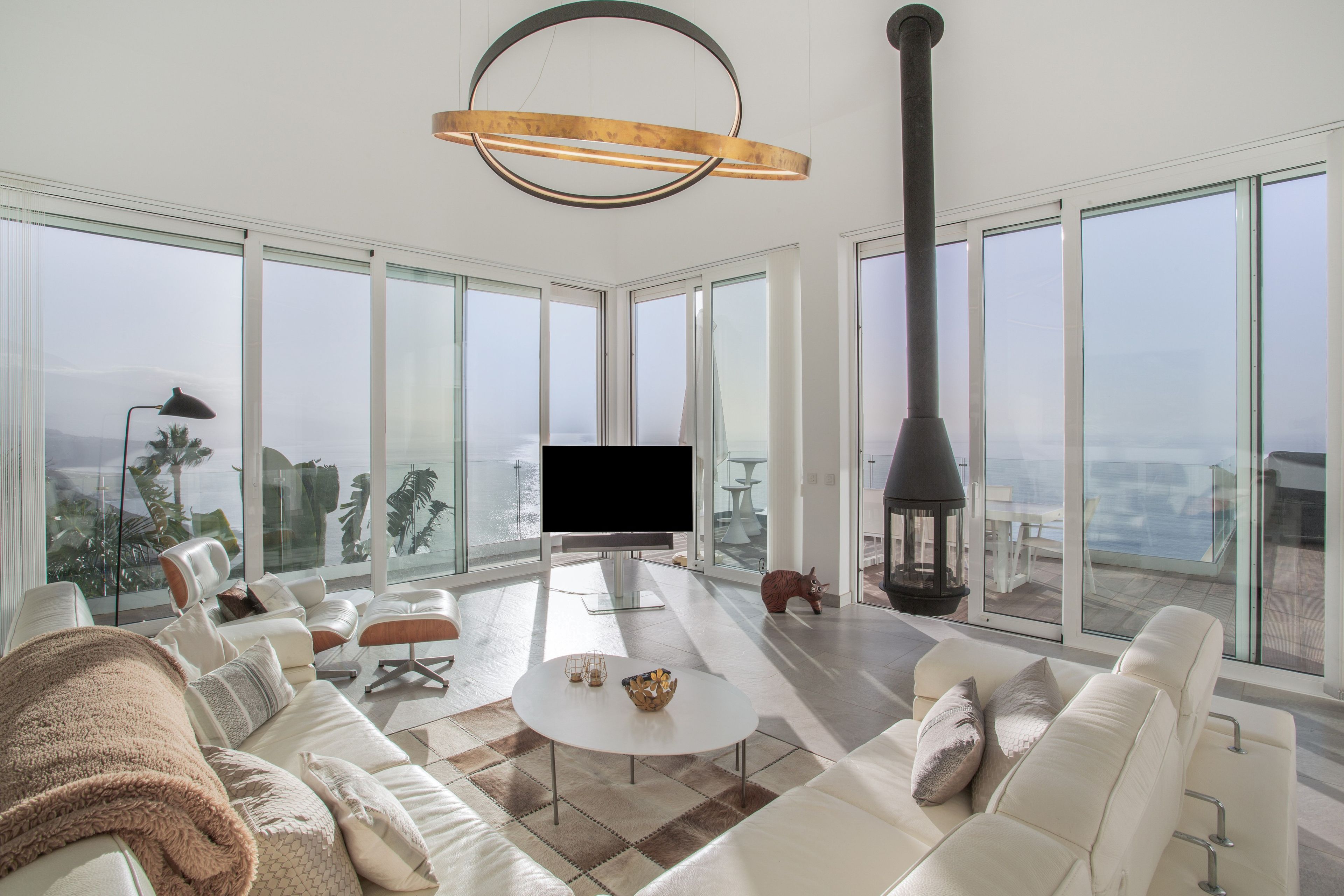 Ein großzügiges Wohnzimmer mit einem großen Fernseher, bequemen Sitzgelegenheiten und Blick auf die Stadt.