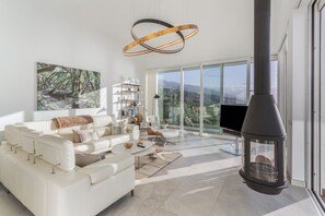 A modern living room with a white sofa, a coffee table, and a fireplace. - Villa 'Crystal Ocean Villa' with Sea View, Heated Pool & Wi-Fi (EL SAUZAL)
