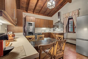 A kitchen with wooden cabinets, stainless steel appliances, and a glass dining table. - Vacation Home "La Hacienda" with Sea View, Private Terrace & Wi-Fi (GARACHICO)