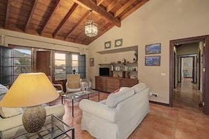 A living room with a white sofa, a glass coffee table, and a lamp. There is a wooden ceiling and a door leading to a balcony. - Vacation Home "La Hacienda" with Sea View, Private Terrace & Wi-Fi (GARACHICO)