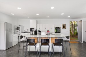 A modern kitchen with a central island, bar stools, a built-in washing machine, and a refrigerator. - Vacation Home "Villa Bahía de Michel" with Sea View, Pool, Garden & Wi-Fi (santa ursula)