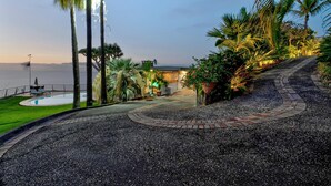 A landscaped area with a pool, palm trees, and a pathway leading to a building. - Vacation Home "Villa Bahía de Michel" with Sea View, Pool, Garden & Wi-Fi (santa ursula)