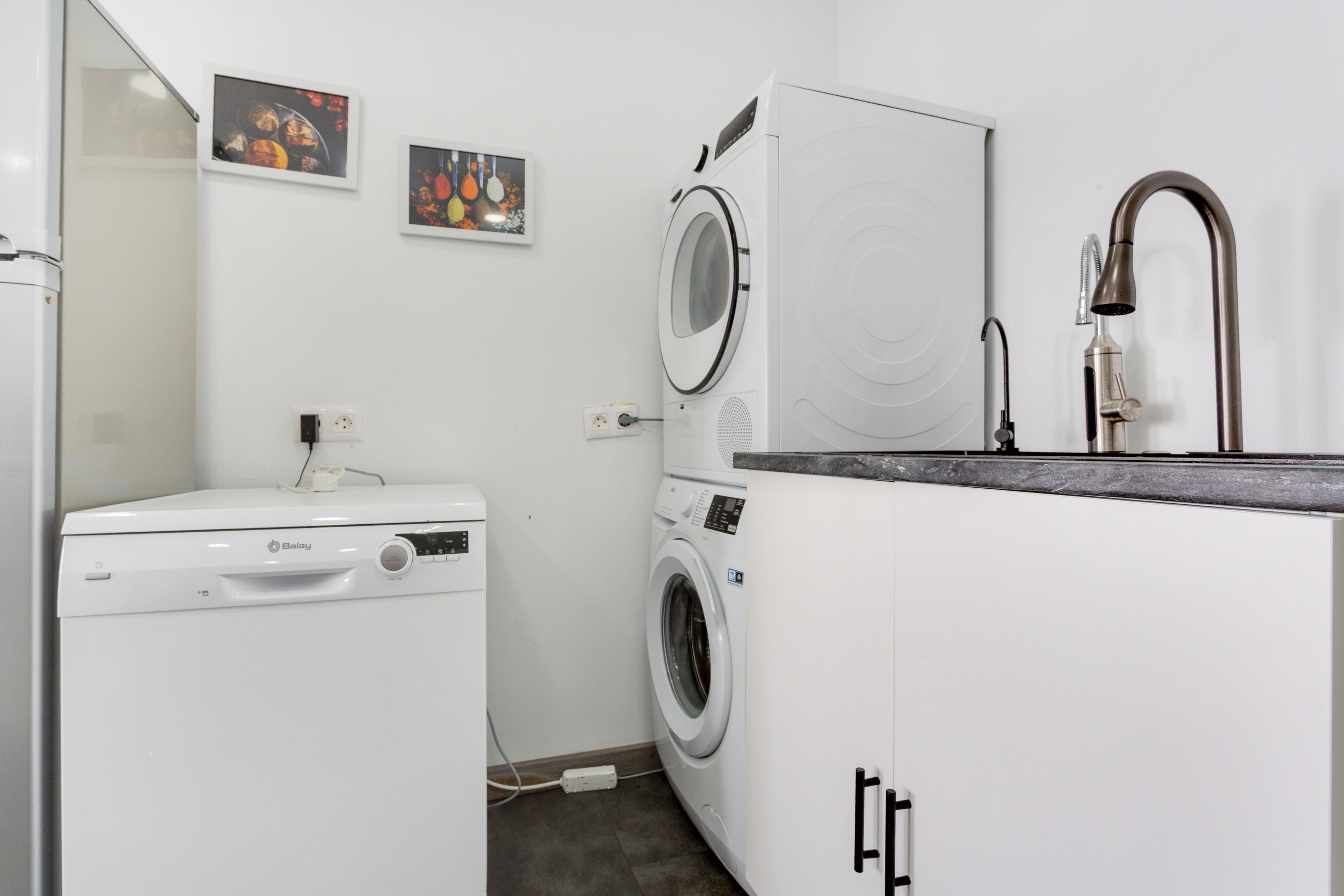 Un lavadero pequeño con lavadora, secadora y un armario con lavabo.
