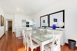 A modern kitchen with white cabinetry, a glass dining table, and a seating area with white chairs. - Vacation Home "Villa Bahía de Michel" with Sea View, Pool, Garden & Wi-Fi (santa ursula)