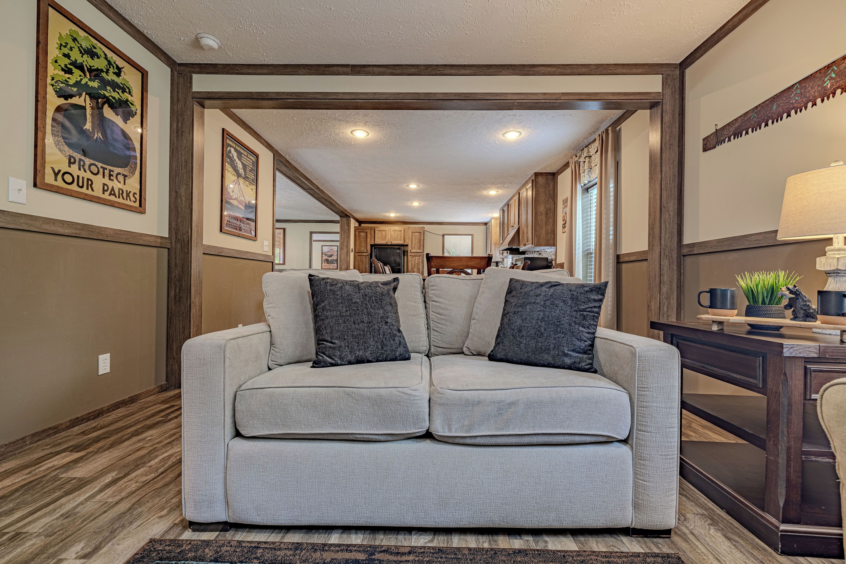 A living room with a grey sofa, a coffee table, and a lamp. There is a wooden floor and a rug.