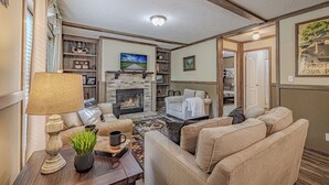 Una sala de estar acogedora con chimenea, asientos cómodos y una estantería.