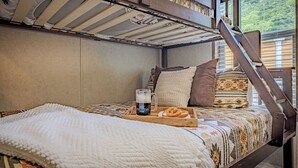 Un dormitorio acogedor con una litera, una bandeja de madera con una taza y un pretzel, y ropa de cama estampada.