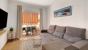 A living room with a sofa, a TV, a small table with a plant, and a painting on the wall. - Holiday Home "Casa Roberto" with Private Balcony, Shared Pool and Wi-Fi (Candelaria)